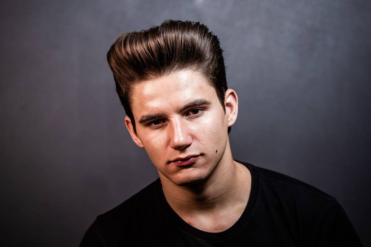 Man applying strong hold pomade to textured hair with fingertips